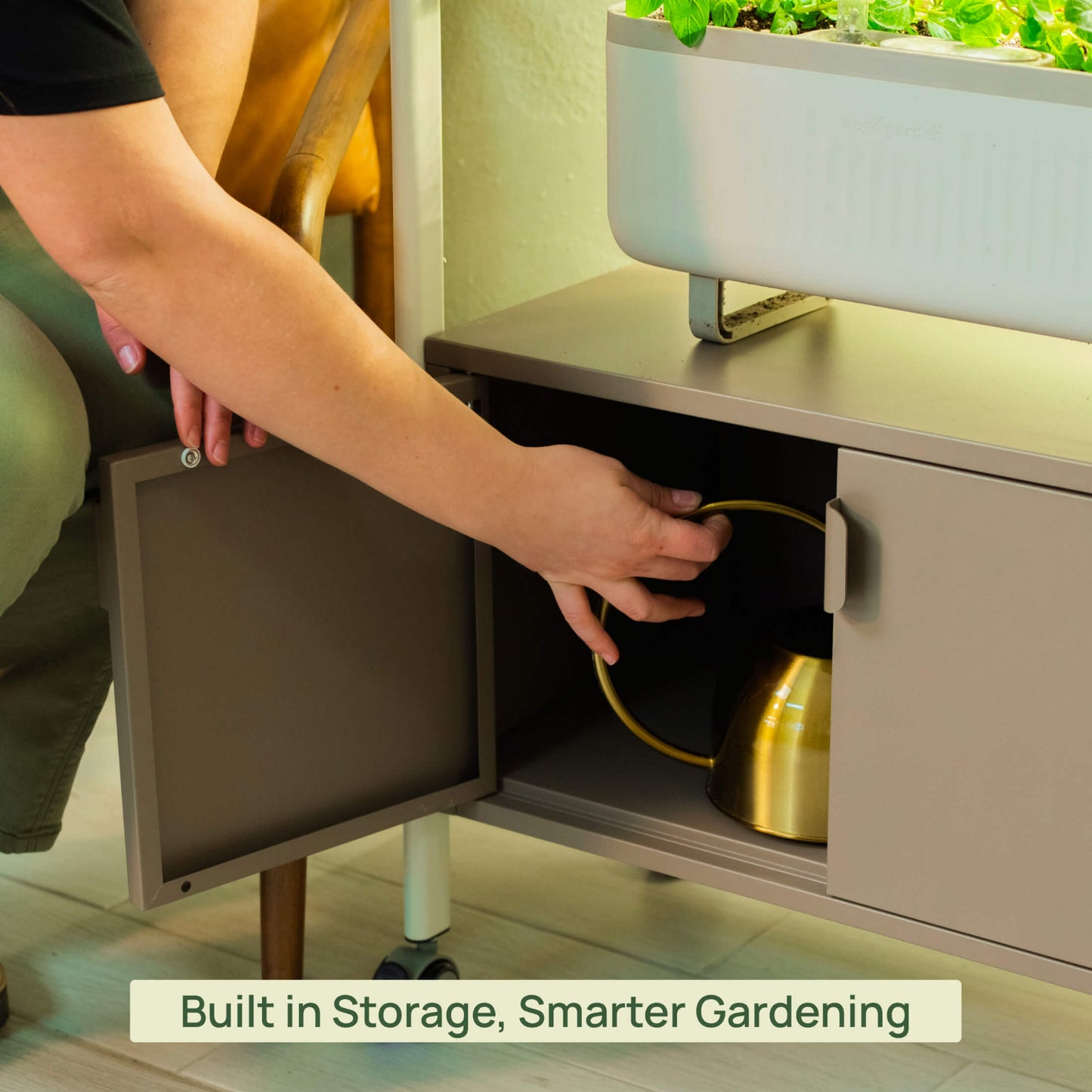 Person opening a cabinet with gardening tools inside, emphasizing built-in storage compartment on the bottom of the 4 Tier Grow Light Garden.