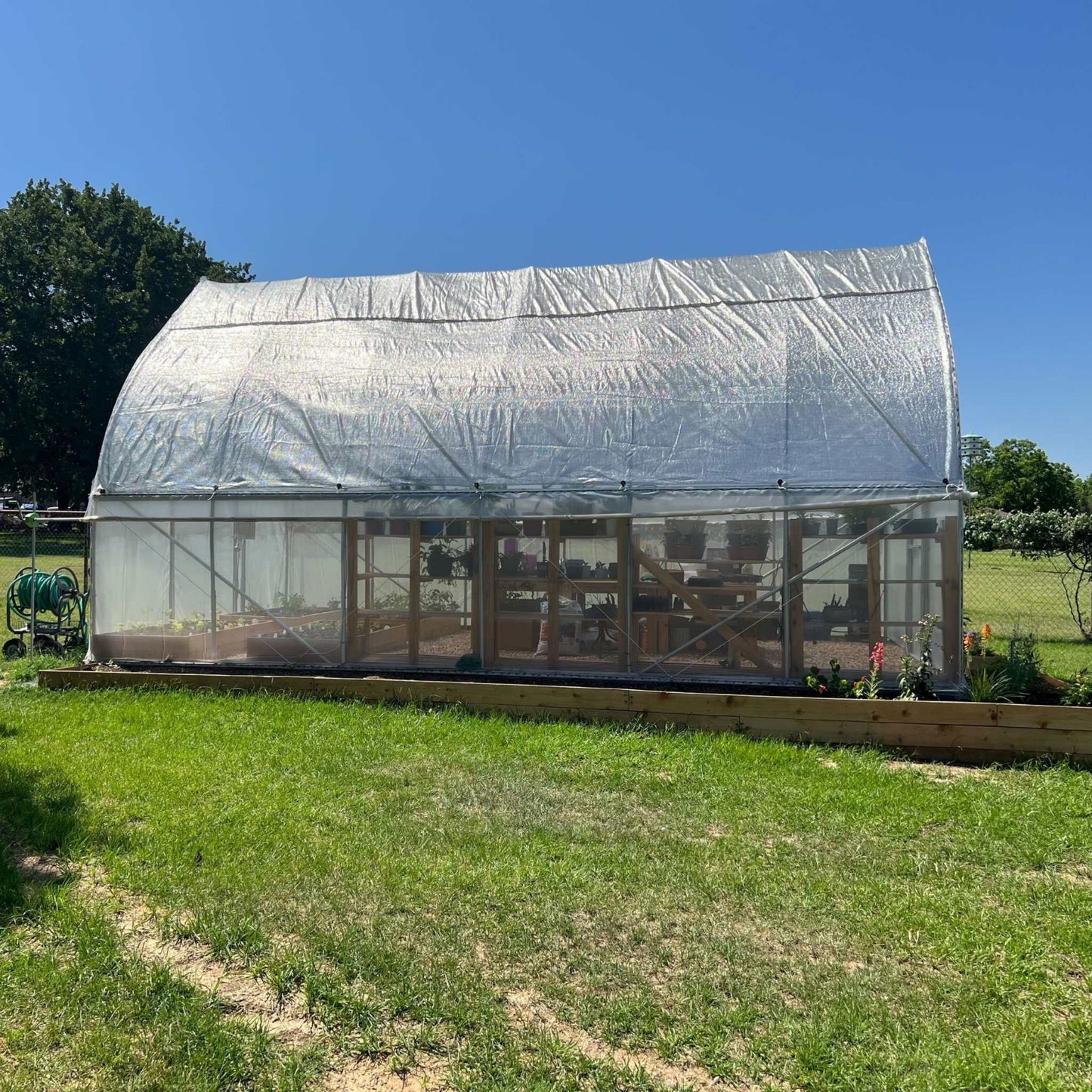 white shade cloth shown in use installed over outdoor greenhouse