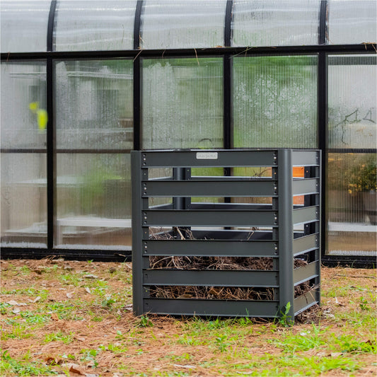 Modular Compost bin in front of a greenhouse in a backyard setting.