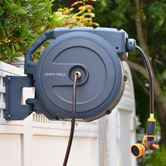 Retractable garden hose reel with attached nozzle, mounted outdoors.