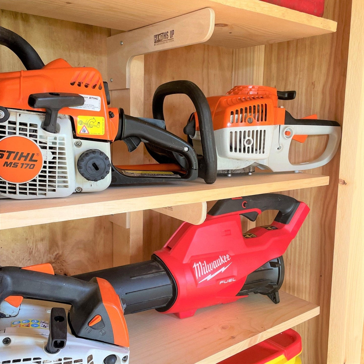 Close-up of a shed shelf brackets for 10 inch shelves installed on the stud and lawn equipment sitting on the shelves.
