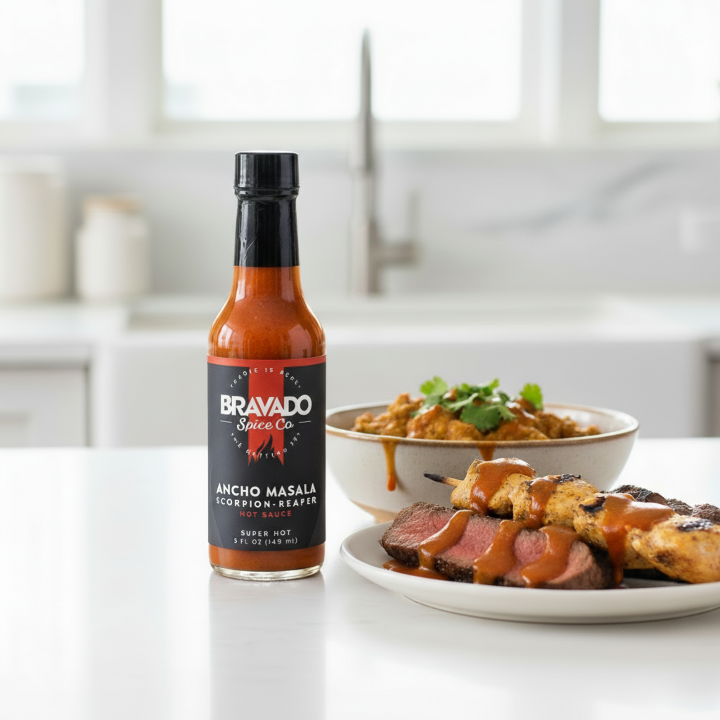 Ancho Masala Scorpion Reaper Hot Sauce bottle on a white kitchen counter beside a bowl of Indian curry and a plate of grilled meats drizzled with spicy hot sauce.