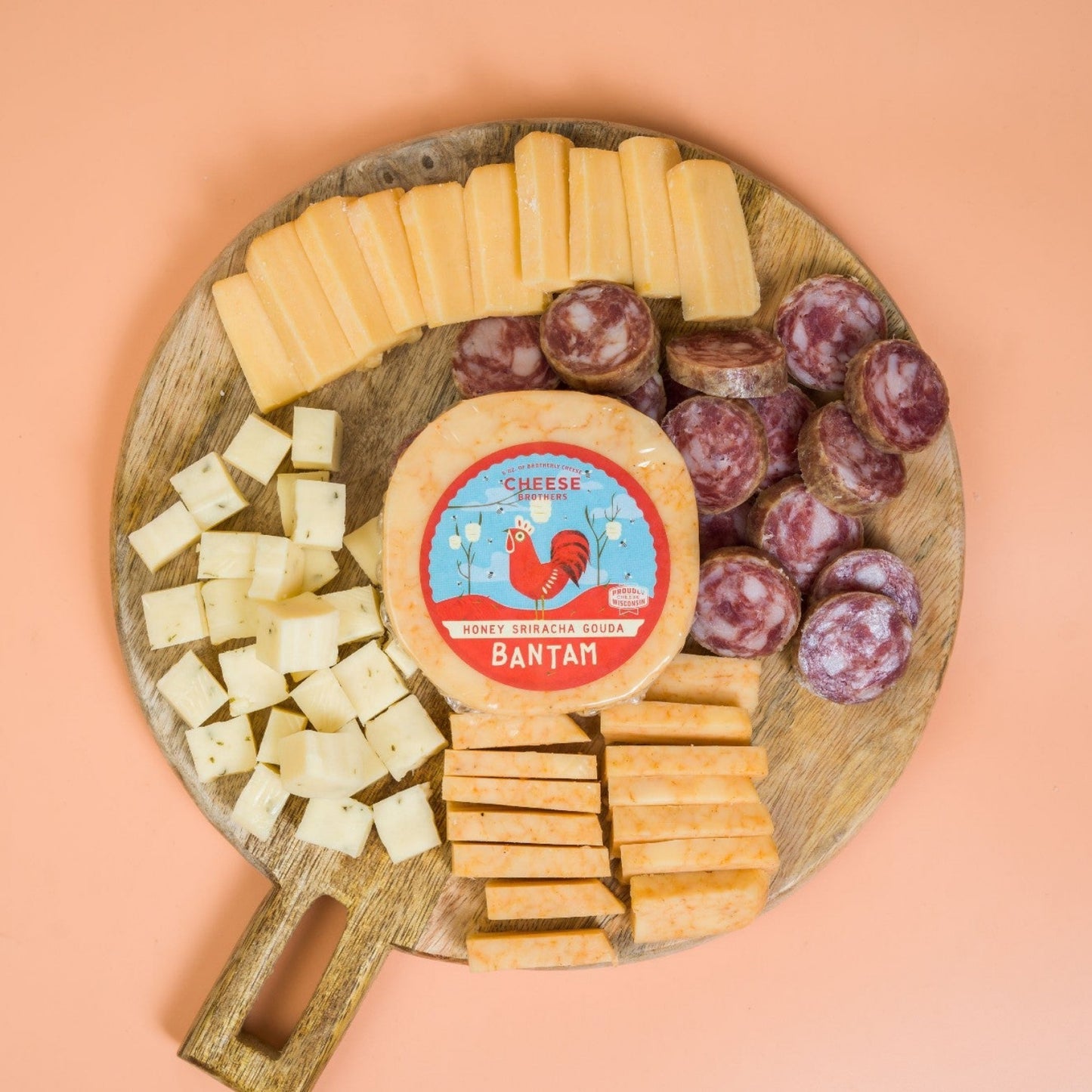 Wooden board with sliced cheese and cured meats on a peach background
