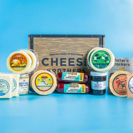 An assortment of gourmet cheeses, meats, and crackers displayed in front of a wooden box