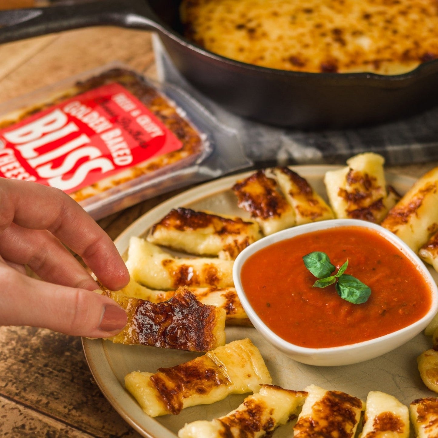 Golden baked bliss cheese sliced and being dipped into bowl of marinara sauce