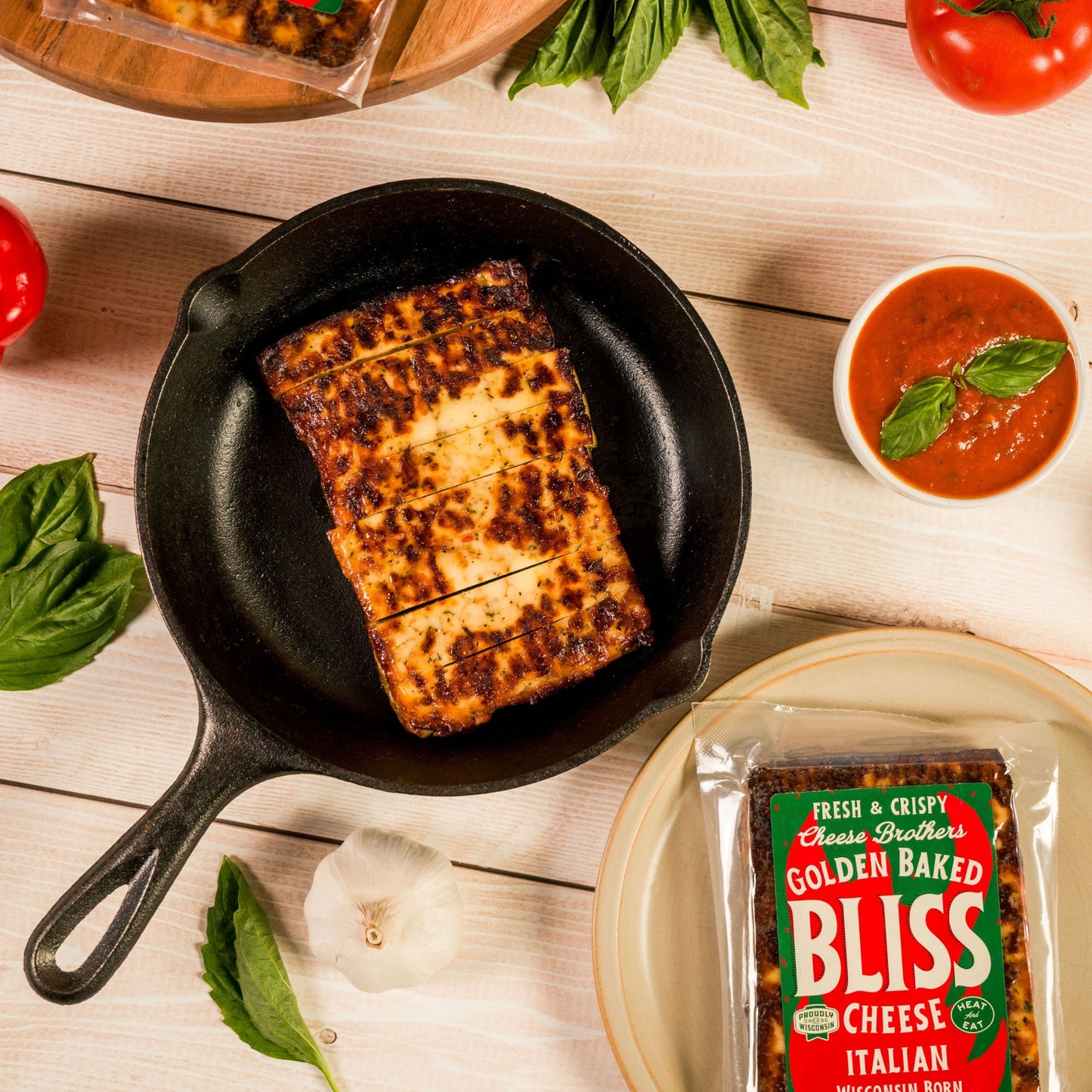 Italian Baked Bliss Cheese in cast iron pan surrounded by peppers, tomatoes and basil