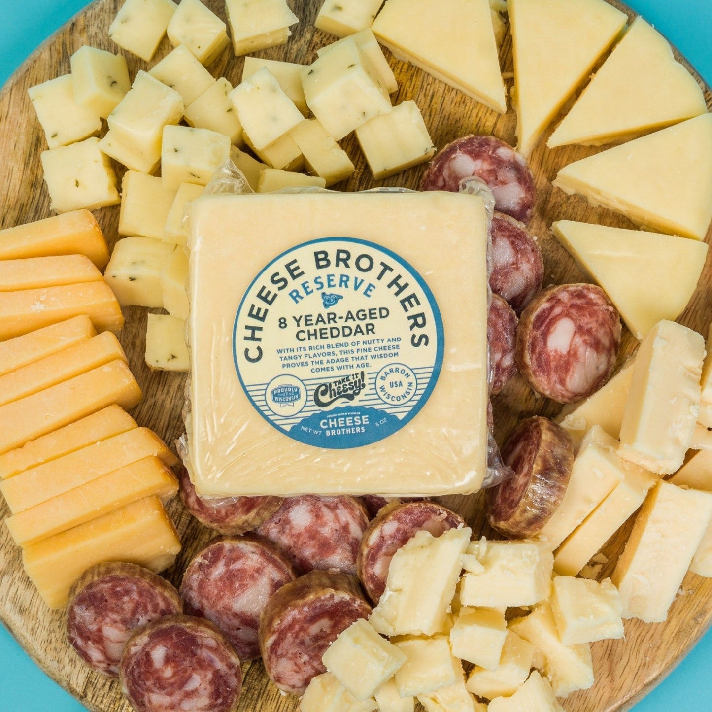 Wooden cutting board with various cheese and sausages on a blue background