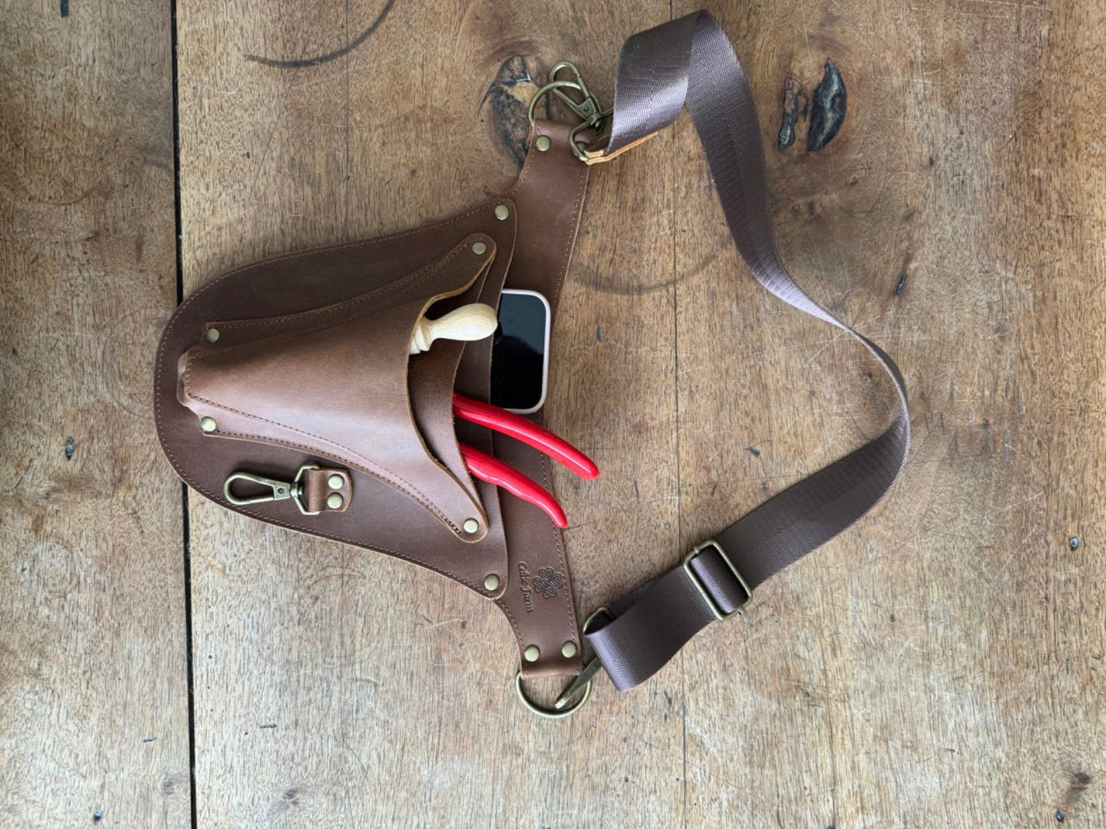 Brown leather holster with tools on a wooden surface