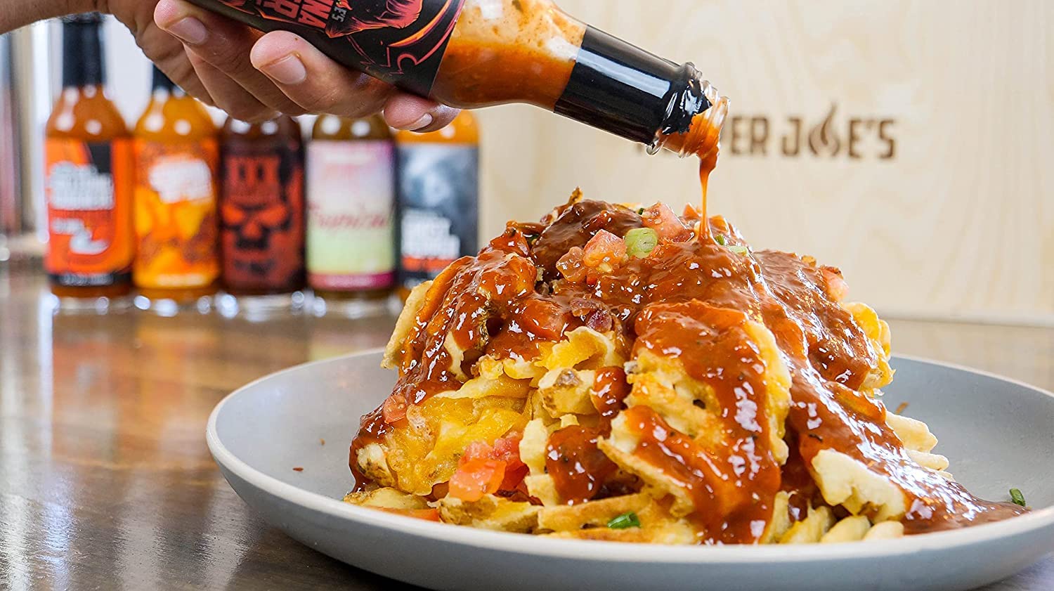 Pepper Joe's Carolina Reaper Hot Sauce - the reaper hot sauce pouring on a plate of fries