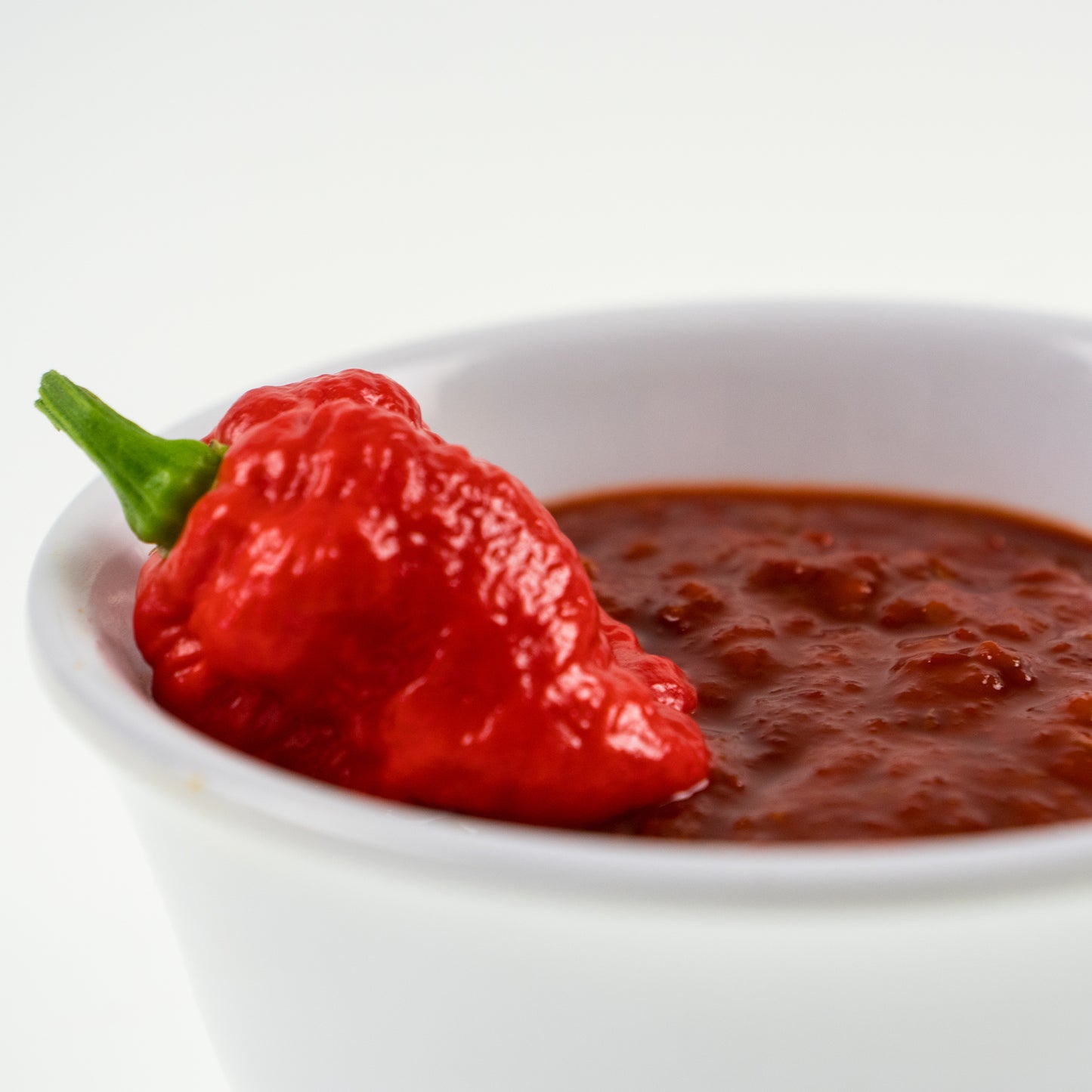 Pepper Joe's Ghost Pepper Mash Puree - Spicy hot pepper mash puree in white bowl with ghost pod on top
