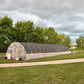 Long greenhouse structure on a grassy area with trees in the background