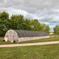 Long greenhouse structure on a grassy area with trees in the background