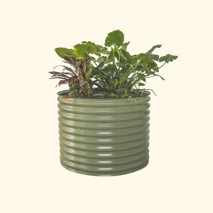 An olive green 32 inch extra tall  42 inch wide round modern metal Garden Bed with colorful flowers and plants on a white background.