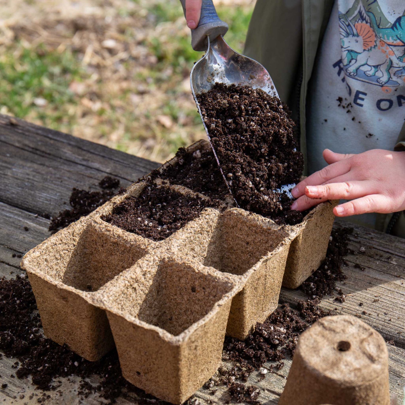 person filling Cowpot, a biodegradable seed starting pot, with soil