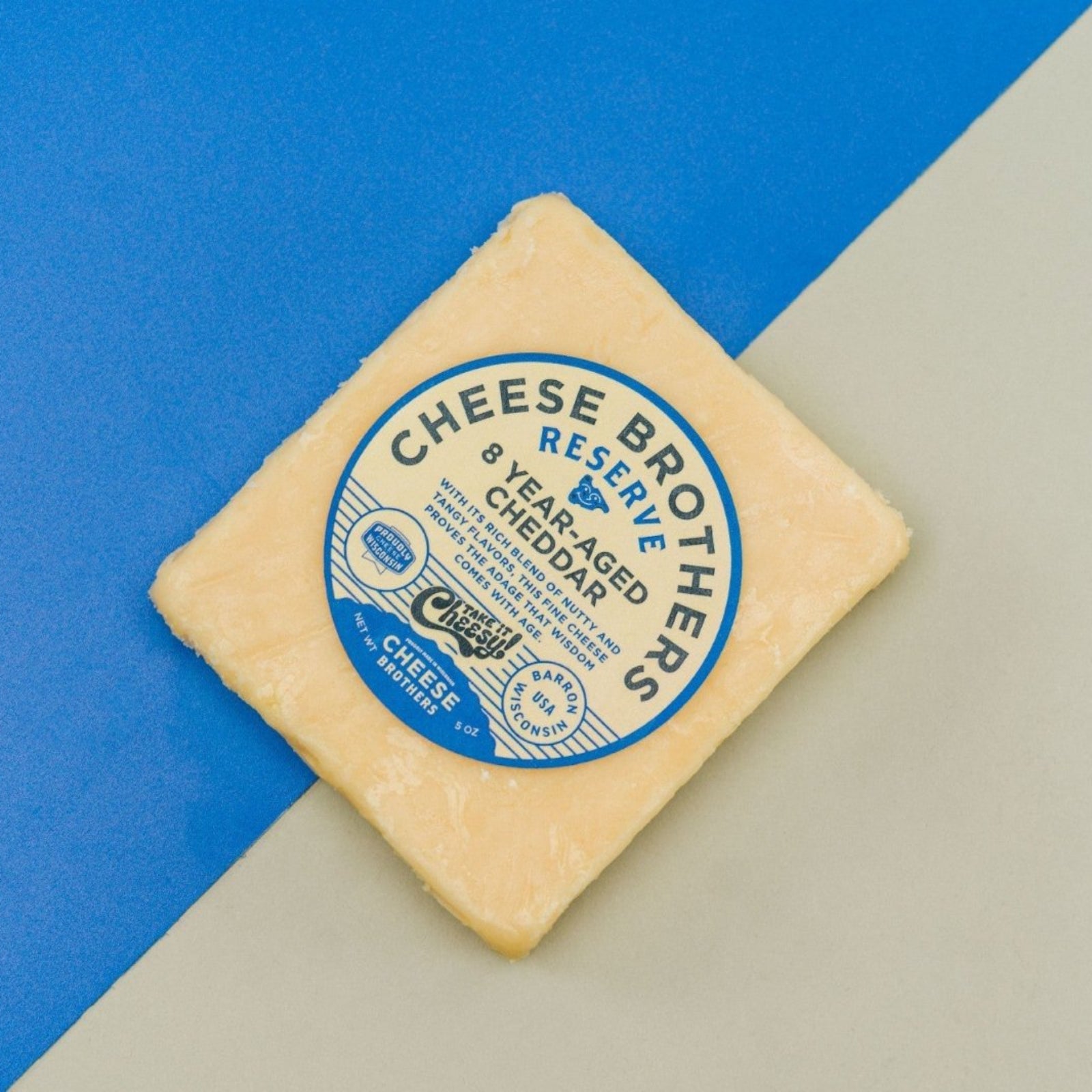 8 year aged cheddar block of cheese presented on a blue and white plain background