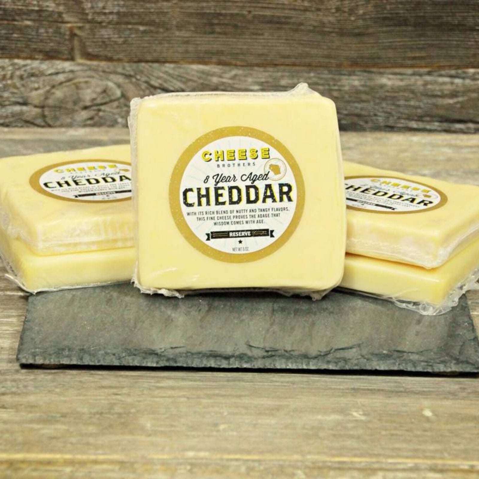 8-year cheddar cheese on slate cutting board on wood background