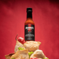  Ancho Masala Scorpion Reaper hot sauce sitting on a pile of food items on a red background