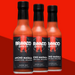 Three bottles of Ancho Masala Scorpion Reaper hot sauce on a red background