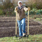 Man using a Broadfork Garden Tool for no-till soil aeration and cultivation in a garden setting