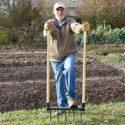 Man using a Broadfork Garden Tool for no-till soil aeration and cultivation in a garden setting