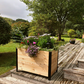 Cedar planter box with plants on a wooden deck in a backyard setting