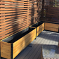 Empty cedar planters on a deck with a slatted wooden wall in the background