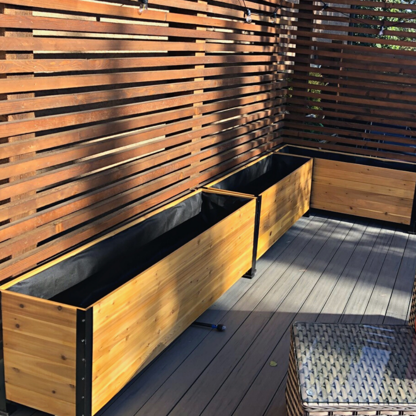 Empty cedar planters on a deck with a slatted wooden wall in the background