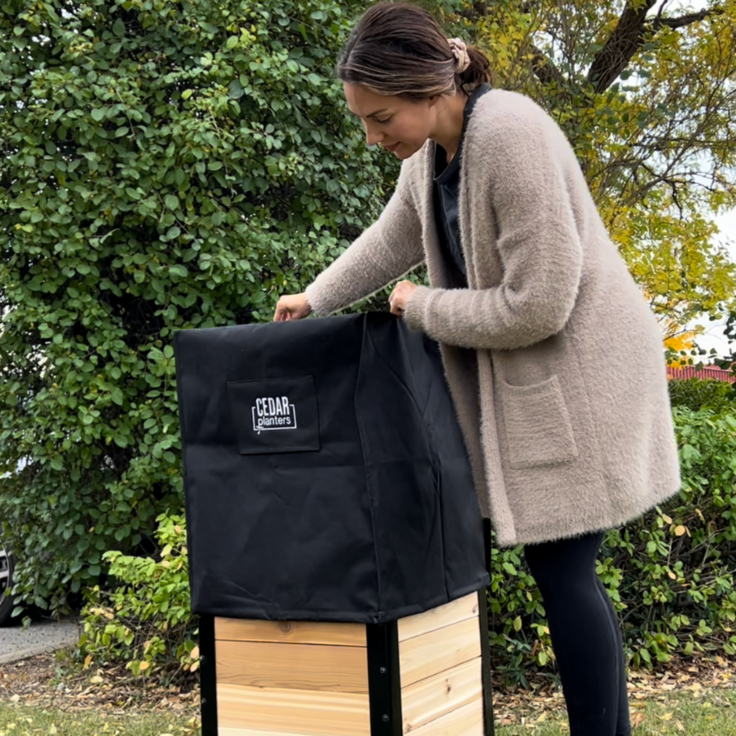 Woman removing Cedar Planters winter cover from planter box in backyard, easy on and off weatherproof planter cover
