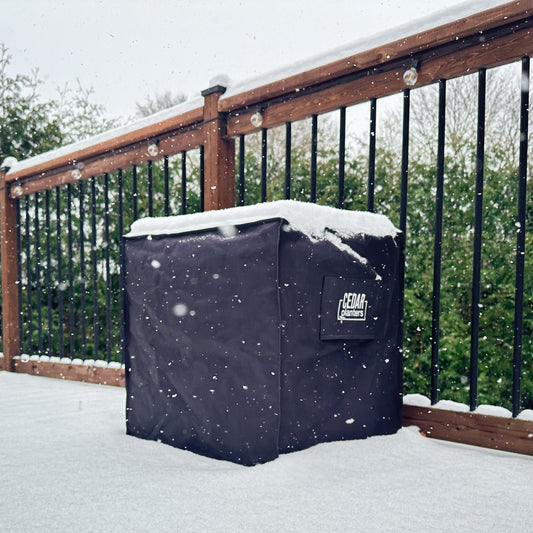 Cedar Planters winter cover with snow cover on a wooden deck during a snowfall.