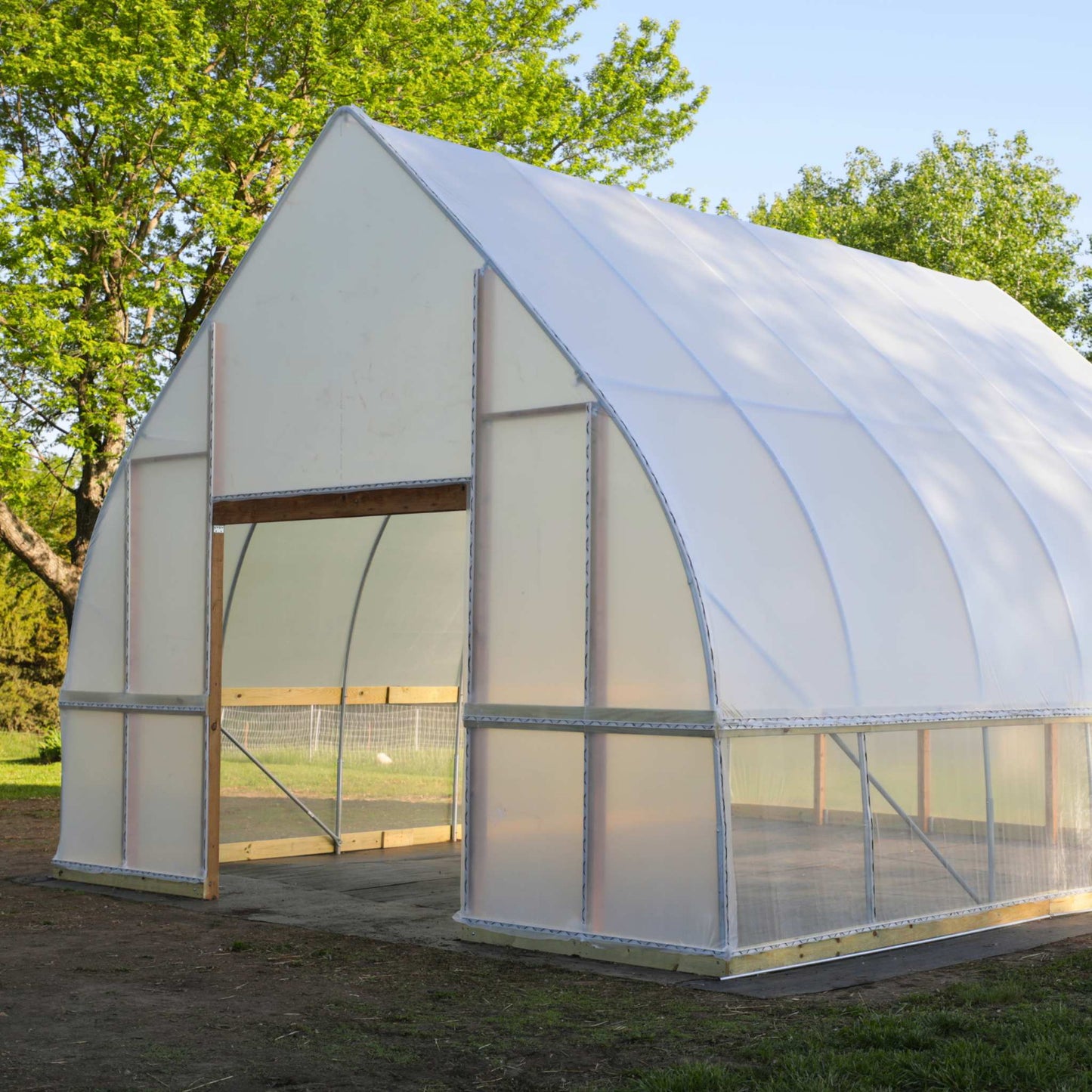 DIY Gothic Hoop House front door angled side view with transparent panels in an outdoor setting