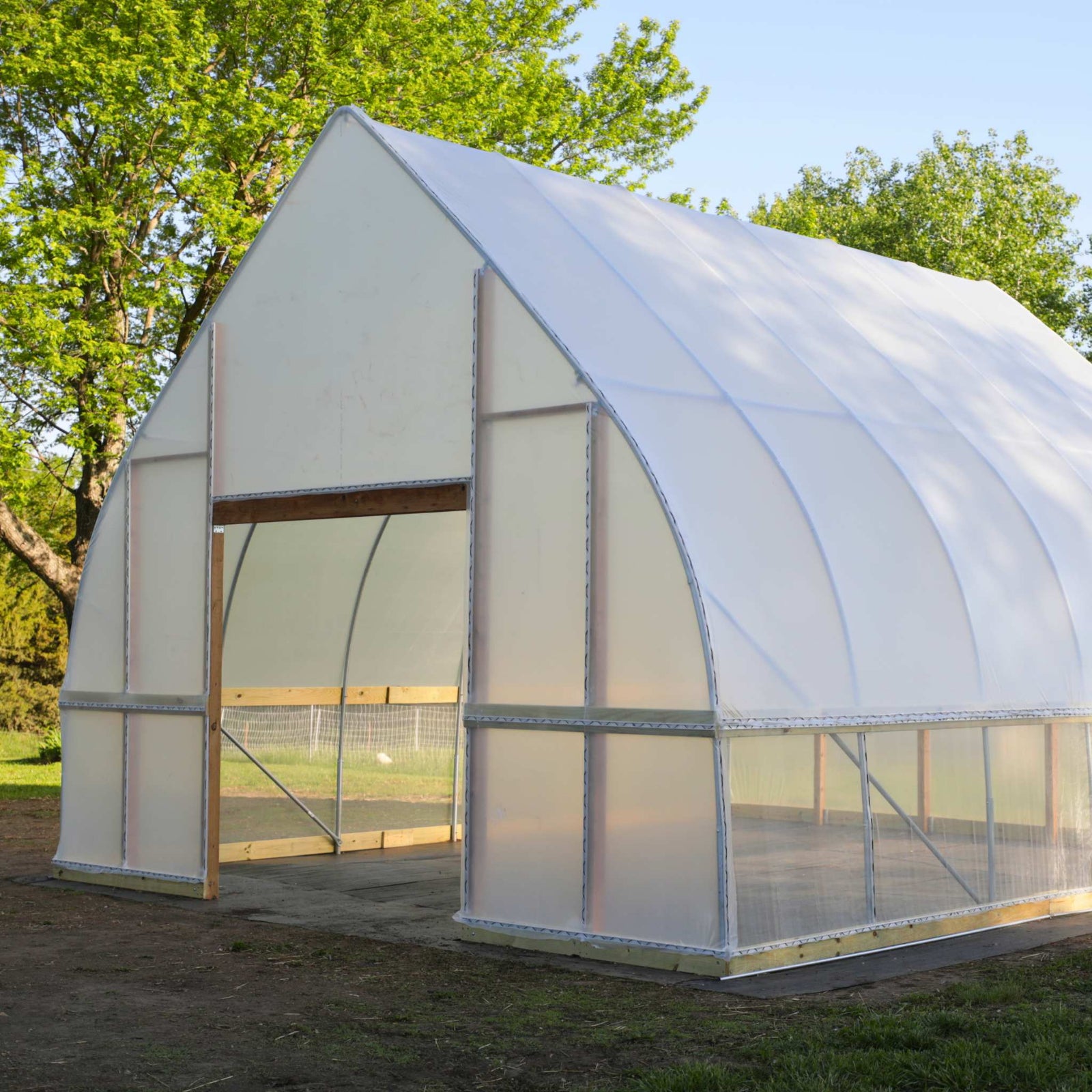 DIY Gothic Hoop House front door angled side view with transparent panels in an outdoor setting