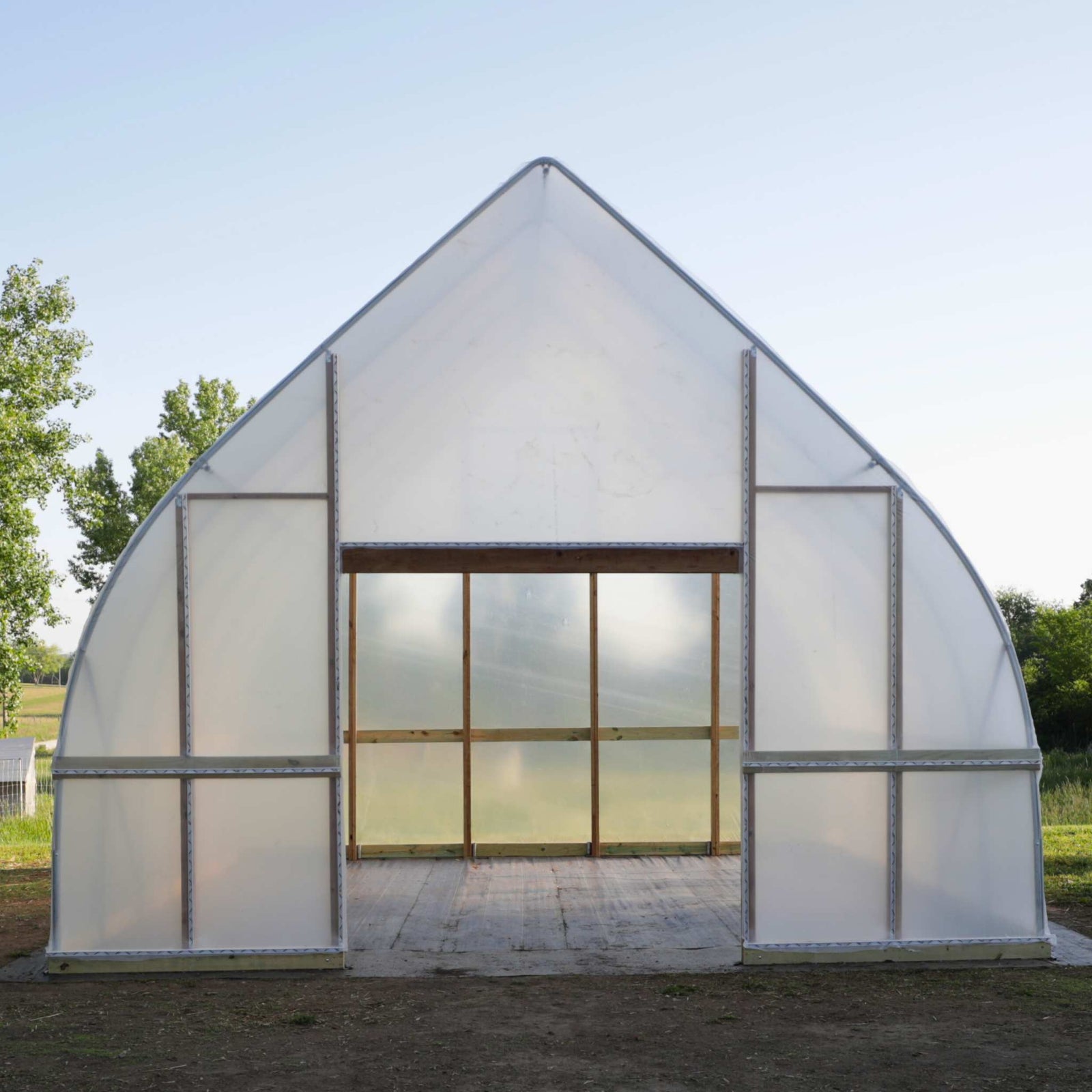 DIY Gothic Hoop House with transparent walls and a sloped roof in an outdoor setting.