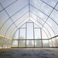Interior of a DIY Gothic Hoop House with a clear plastic roof and walls with wind braced installed.