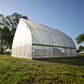 Exterior rear view of a DIY Gothic Hoop House with a clear plastic exterior in an outdoor setting.
