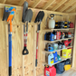 Garden tools and equipment organized on shelf and hooks hanging on the wall inside an unfinished shed.