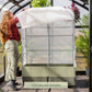 Person setting up the EZCube Cover System on an EZCube Self-Watering Planter inside a greenhouse.