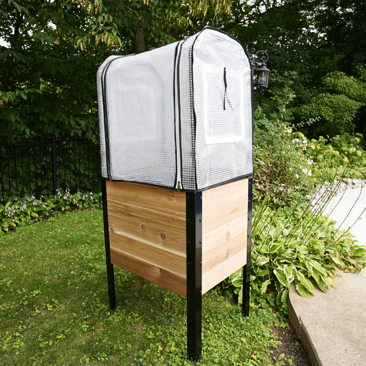 Wooden planter box with a greenhouse cover installed in a garden setting