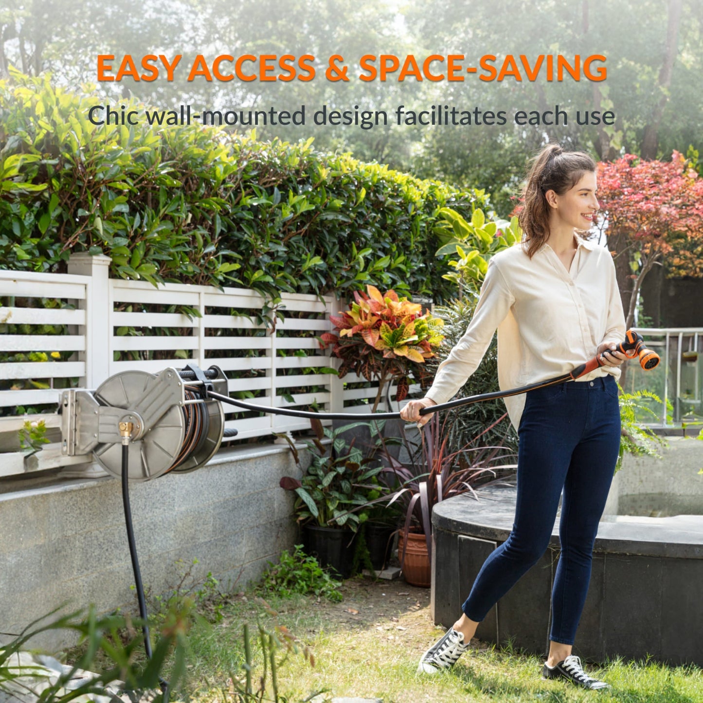 Woman holding a garden hose stored in the heavy-duty wall-mounted  stainless steel hose reel in a garden setting with text outlining easy access and space saving. 