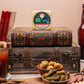 Horseradish Cheddar block on stacked book and wooden chest with Bloody Mary, olives, pickles, and sliced summer sausage
