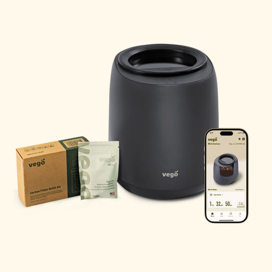 Kitchen Composter in black with a filter refill kit, Vego tabs, and a phone with the included app visible.