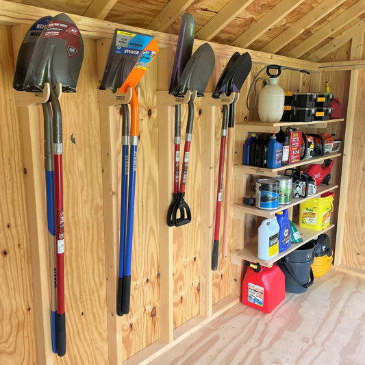 Garden tools and equipment organized on shelf and hooks hanging on the wall inside an unfinished shed.