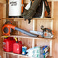 Close-up of a shed shelf brackets for 10 to 12 inch shelves installed on the stud and lawn equipment sitting on the shelves. 