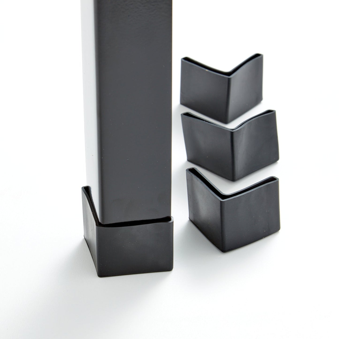 Set of black sleeve feet installed on bed legs on a white background