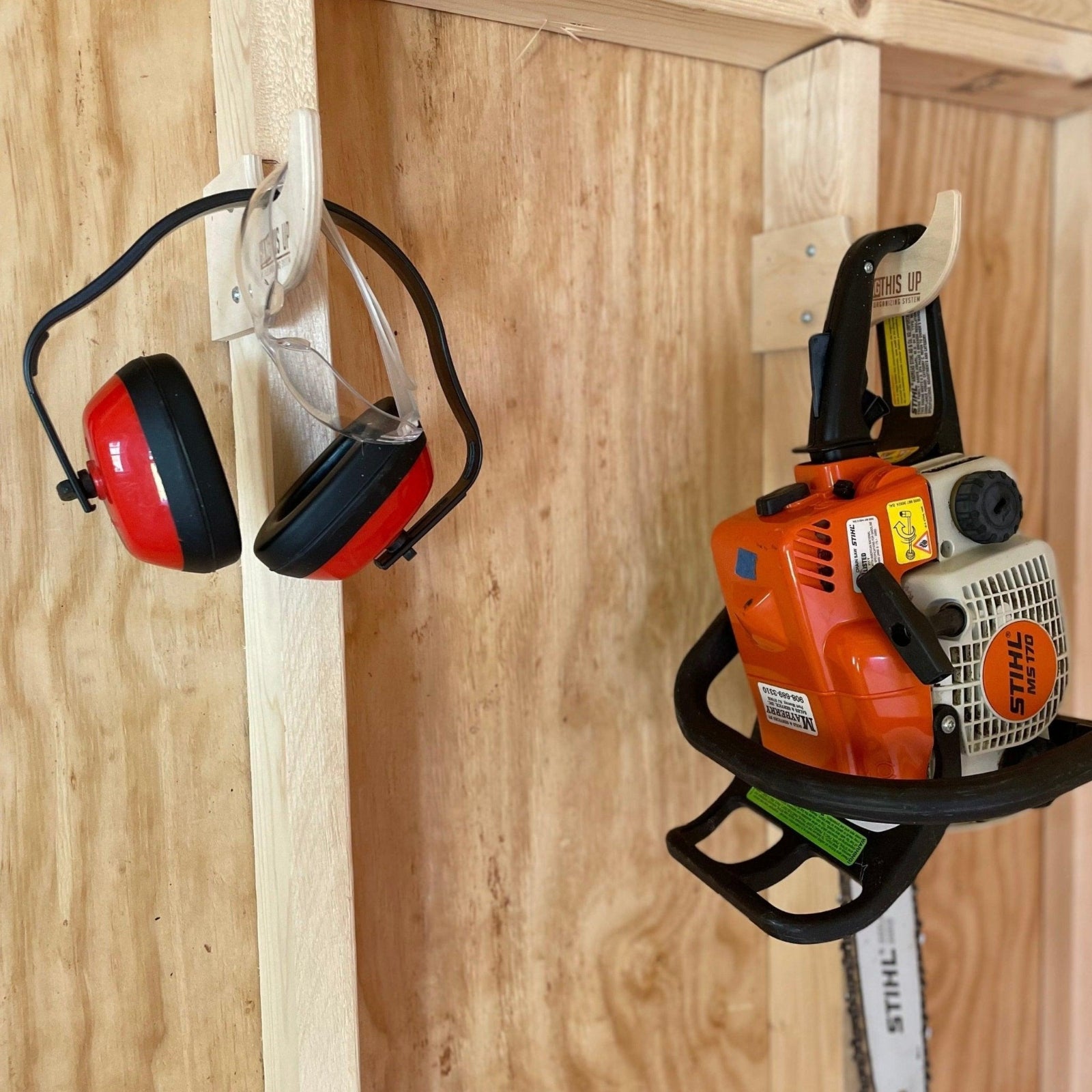 Close-up of a miscellaneous hook organizers installed on studs and with yard tools hanging from the hooks.