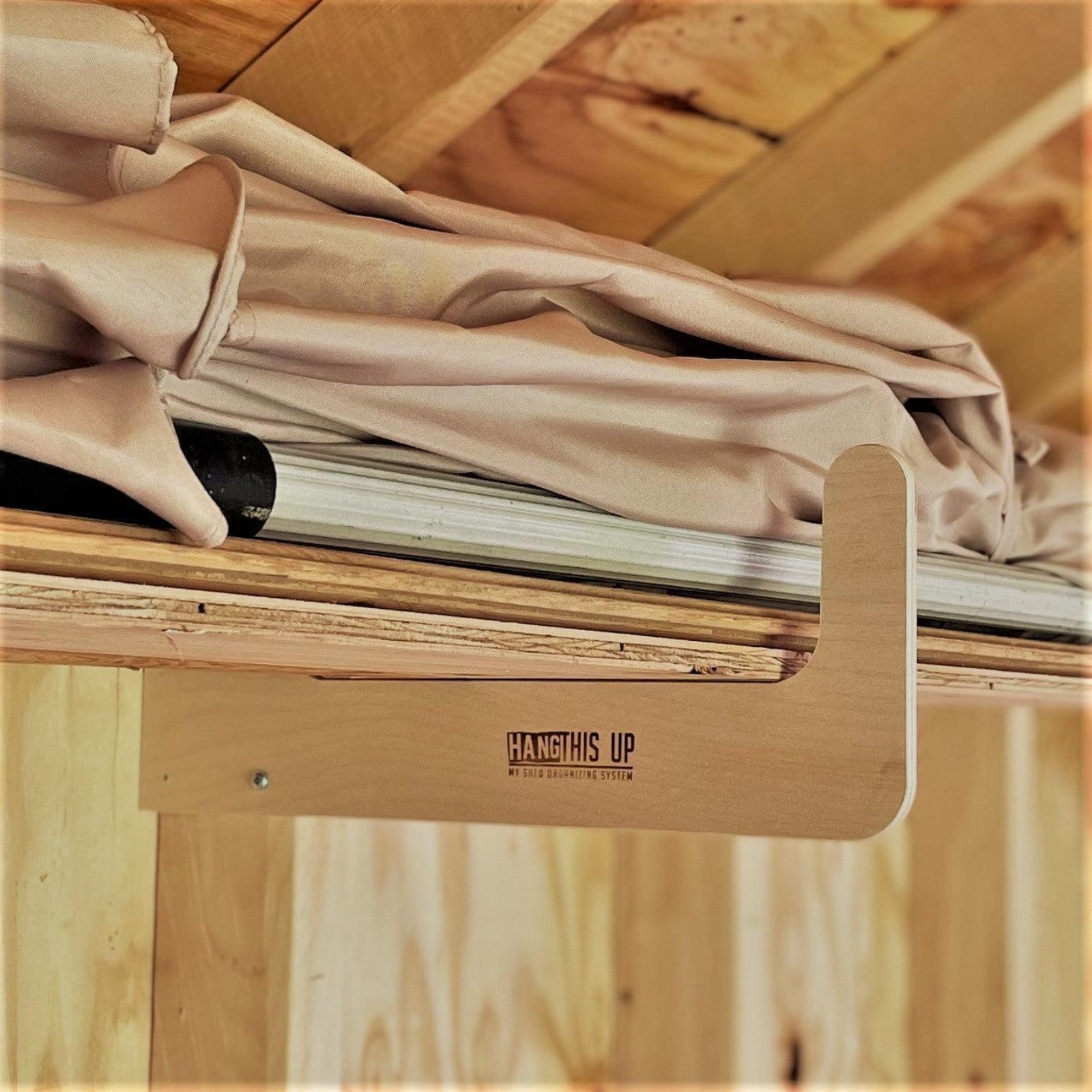 Close-up of a storage organizer rack installed on the stud with an outdoor umbrella, aluminum pole, and wood stored neatly on the rack. 