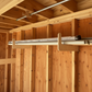 Stud-mounted storage organizer rack holding multiple long PVC and aluminum pipes neatly organized inside an unfinished shed.