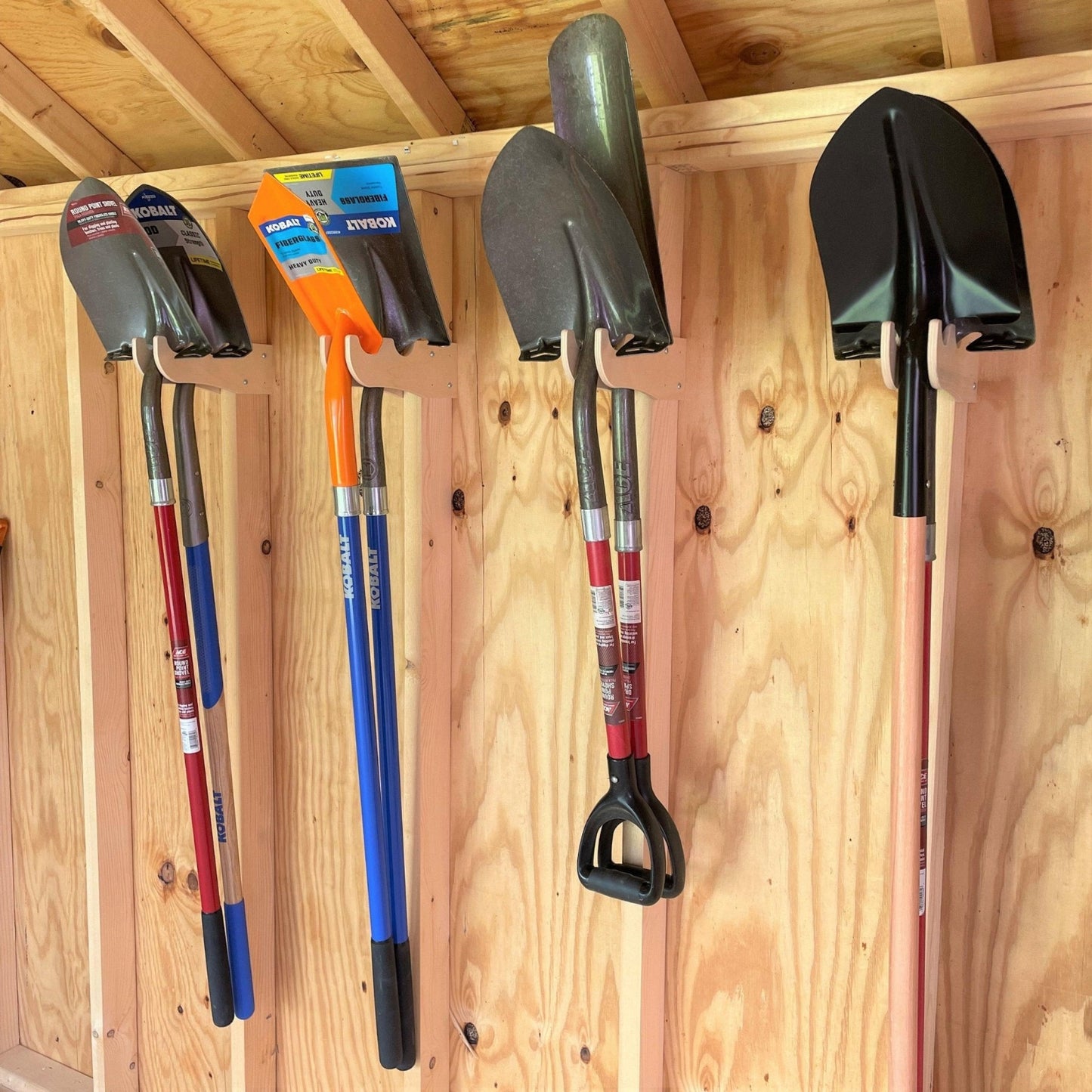 Four pairs of the Garden Yard Tool Organizers installed inside an unfinished shed with shovels hanging  neatly. 