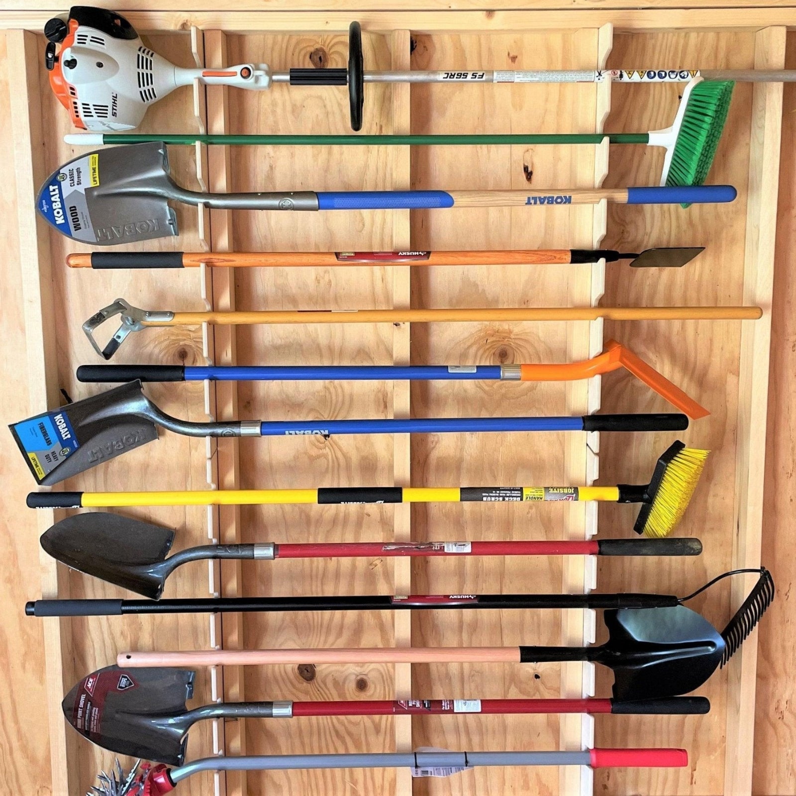 Vertical Garden Tool Organizer installed on an unfinished shed wall with various garden tools neatly organized hanging on the organizer. 