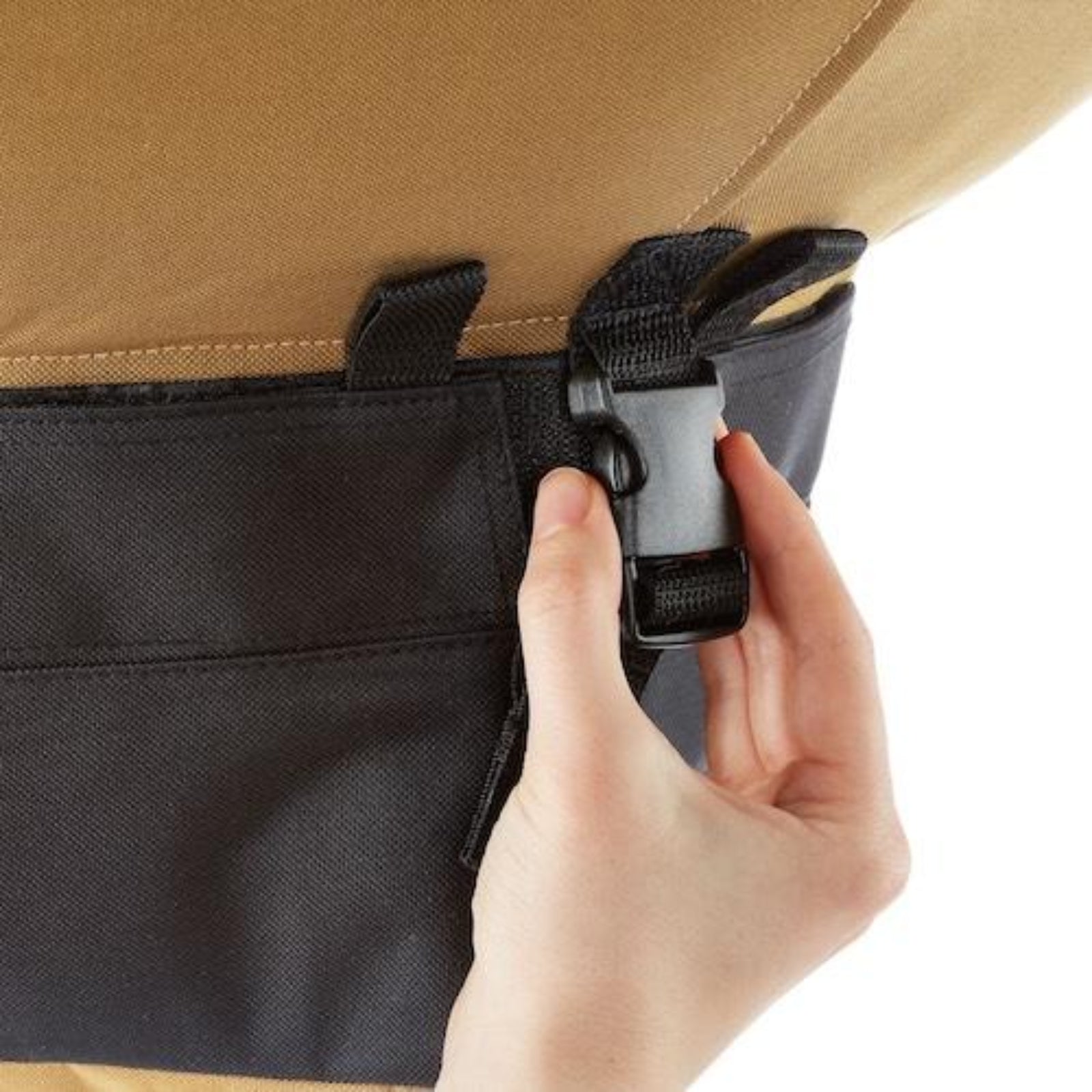 Hand opening a black buckle on the bottom of the Urban Worm Bag. 
