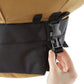 Hand opening a black buckle on the bottom of the Urban Worm Bag. 